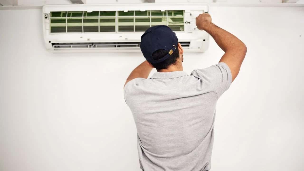 Certified HVAC technician repairing home air conditioner in Ottawa home