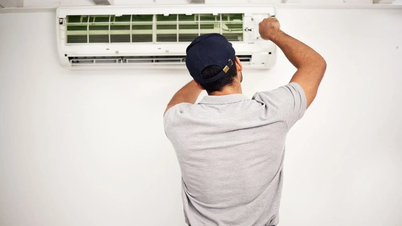 Certified HVAC technician repairing home air conditioner in Ottawa home